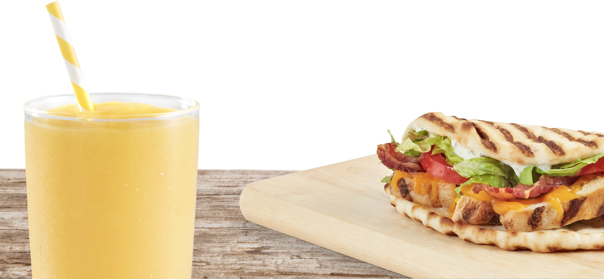 Tropical smoothie cafe flatbread on a wooden platter with a yellow tropical smoothie in a glass with straw