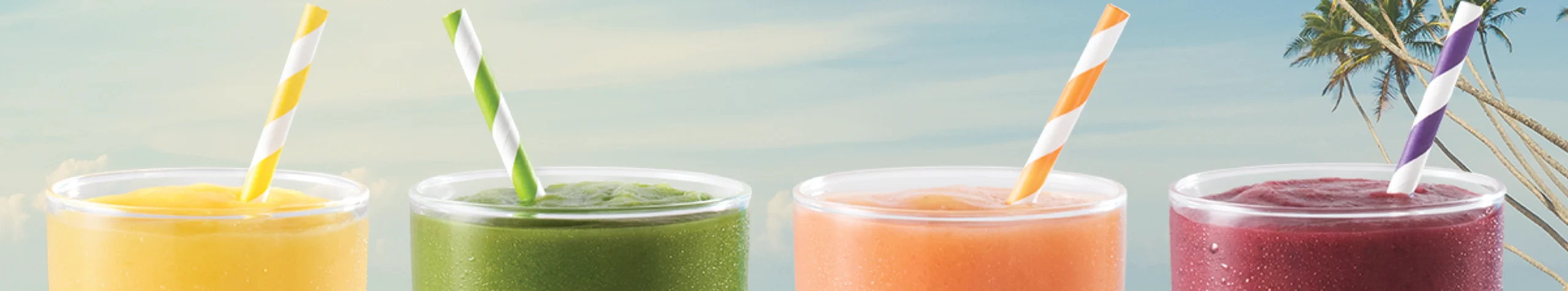 4 glasses of yellow, green, peach and maroon Tropical Smoothies with a coconut tree and blue sky background.